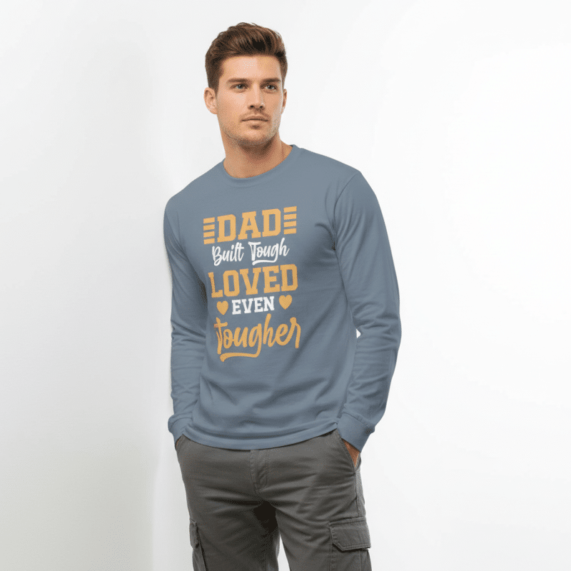 Garment-dyed heavyweight long-sleeve shirt in soft cotton, relaxed fit, pre-shrunk, featuring "Dad Built Tough Loved Even Tougher" design.